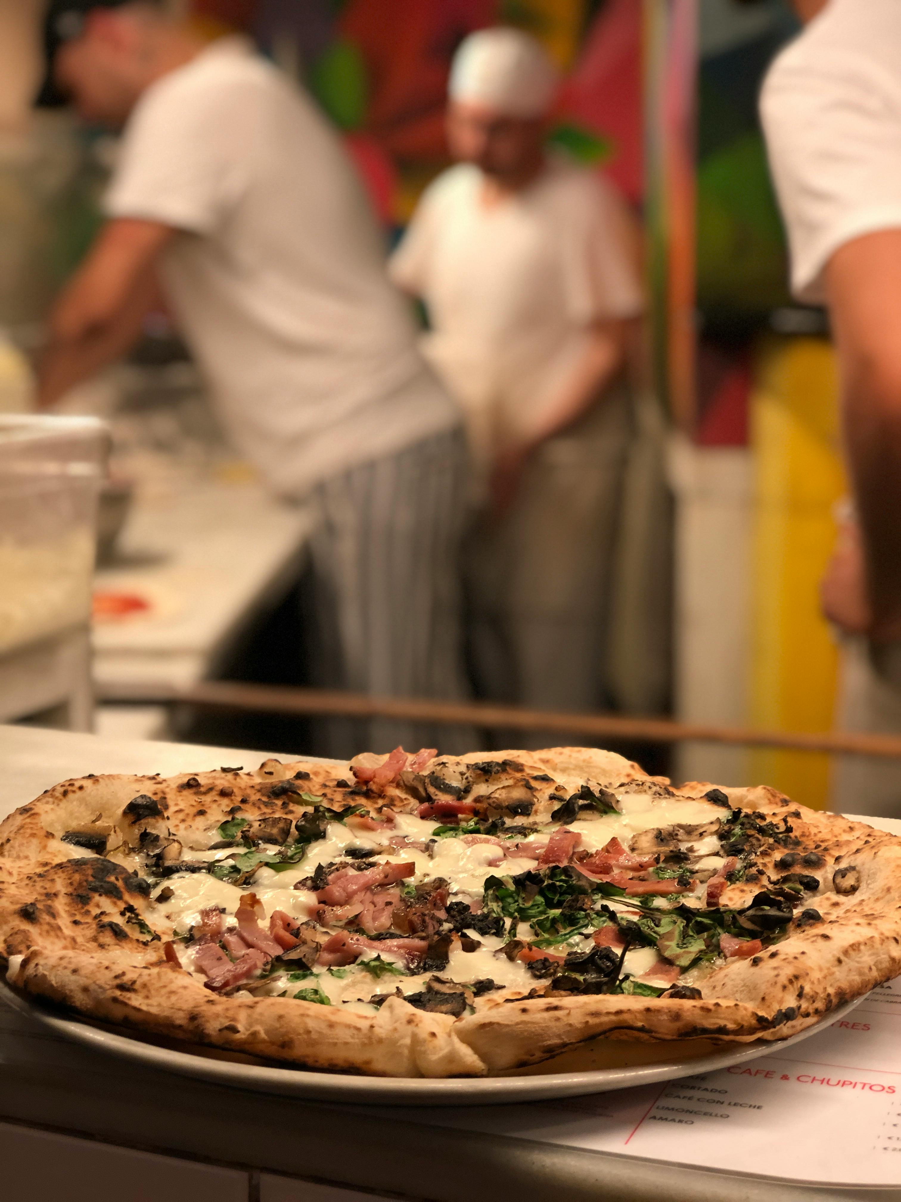 Neapolitan pizza on counter with chefs working in background