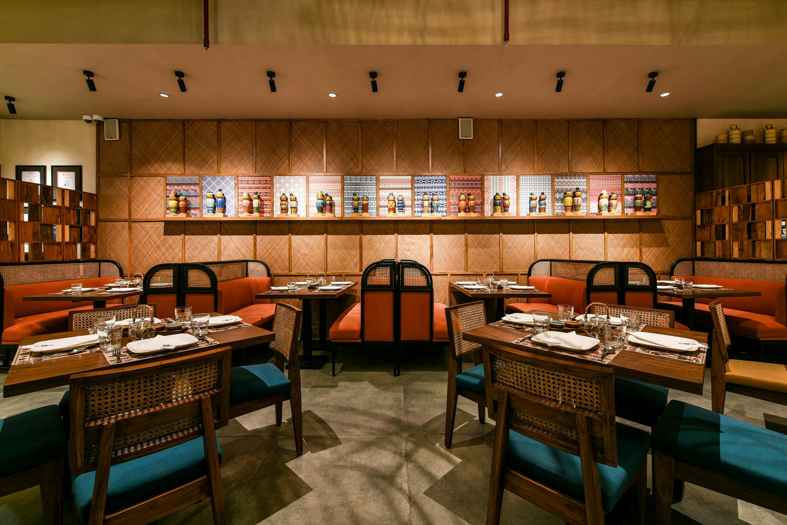Stylish restaurant interior with orange banquettes, woven chairs, patterned wall art